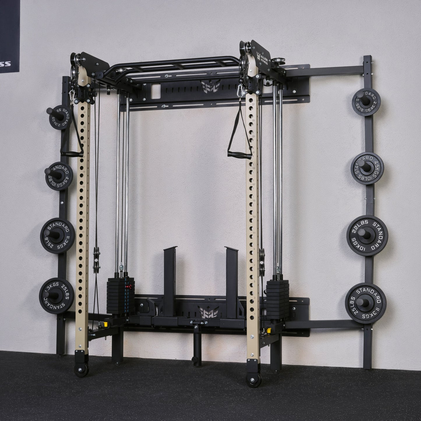 Gym equipment with weight plates on a gray floor against a white wall.