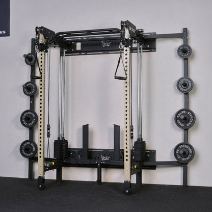 Gym equipment with weight plates on a gray floor against a white wall.