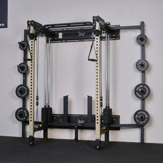 Gym equipment with weight plates on a gray floor against a white wall.